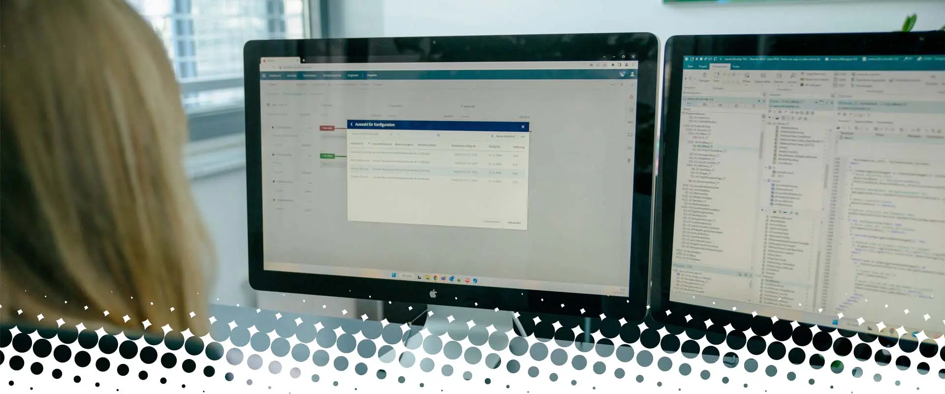 Eine Person sitzt vor zwei Monitoren. Auf den Bildschirmen sind eine geöffnete Software-Anwendung und Programmcode zu sehen.